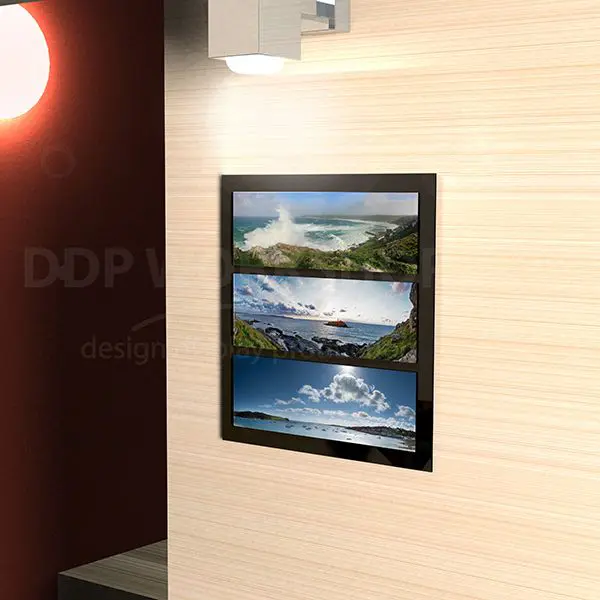 Wall-mounted panoramic picture frame with a black border, displaying three landscape images in a vertical layout under soft lighting.