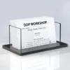 Sleek acrylic business card holder with clear upright panels and black base for desk or counter display.