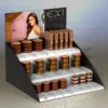 Three-tier black and white acrylic cosmetic display stand with clear product organisers and branded header panel