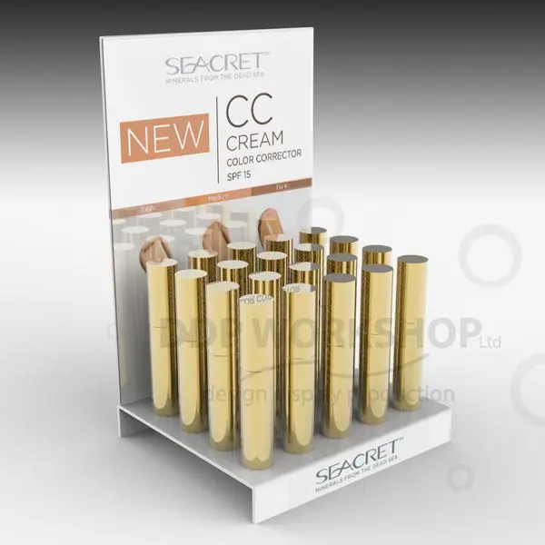 White acrylic mascara counter display stand with gold cylindrical tubes and branded graphic header.