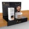 Black acrylic countertop display stand showcasing beauty products with a promotional graphic panel and branded shelf lip.