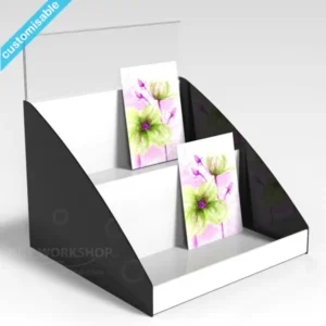 Two-tier black and white acrylic card display with floral greeting cards and a clear header panel for signage.