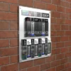 Wall-mounted leaflet display board on brick wall holding multiple brochures in clear holders, including 1/3 A4 and A5 sizes.