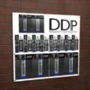 Wall-mounted leaflet display board with DDP branding, holding a mix of 1/3 A4, A5, and A4 brochure holders on a brick wall.
