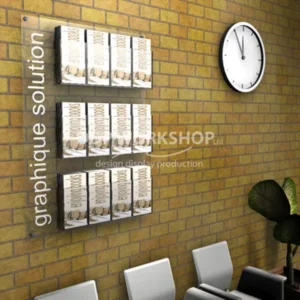 Modern leaflet wall board with side-mounted “graphique solution” branding, holding multiple brochure stacks in a waiting room.