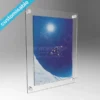 Wall-mounted clear acrylic picture frame with a snowboard image insert, polished finish, and round satin silver wall mounts.