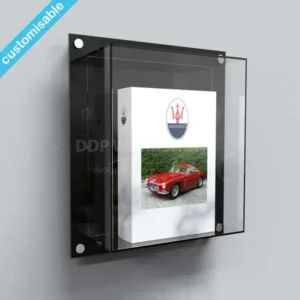 Wall-mounted acrylic display case with black back panel showcasing a collectible book featuring a classic red Maserati.