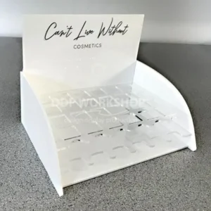 White and clear acrylic curved countertop lipstick display stand with a branded header and multiple tester slots.