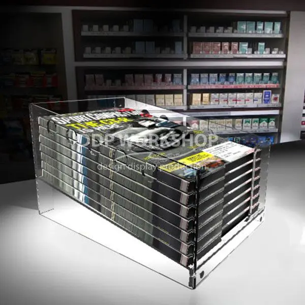 Clear acrylic countertop dump bin filled with magazines in a retail setting