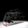 Clear acrylic crescent-shaped wine display stand holding seven wine bottles with a central wine glass, set against a dramatic black background.