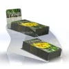 Clear acrylic two-tier counter display stand holding stacks of "Blooms" magazines with curved side panels.