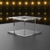Clear acrylic square cake separator with open fillable center, polished edges, and tiered design, displayed against a black backdrop with golden lights.