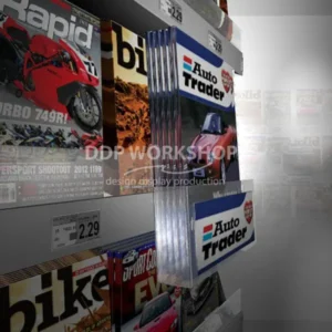 Auto Trader magazines displayed using a clear acrylic parasite merchandising display hooked onto a retail shelf among other magazines.