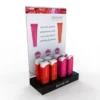 Balmkind lip balm retail counter display with vibrant packaging, branded black acrylic base, and large promotional back panel.