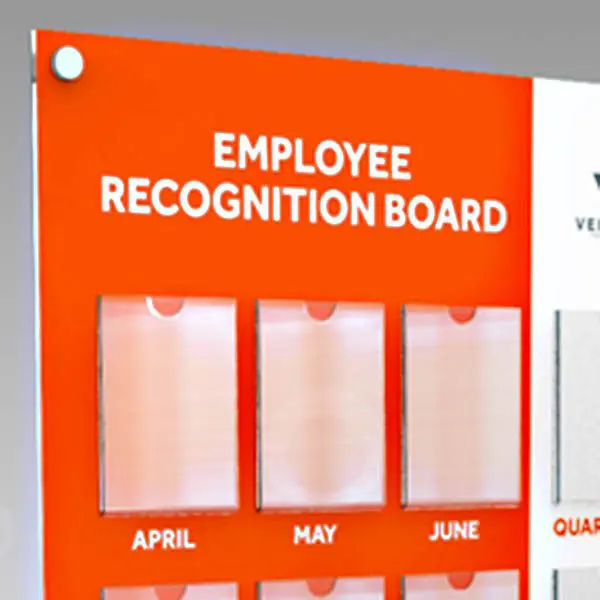 Close-up of an Employee Recognition Board with clear acrylic pockets labeled April, May, and June, and bold white title text on an orange background.