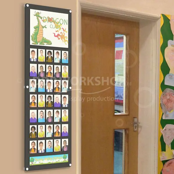 Classroom photo board with dragon-themed header and student portraits, mounted beside a school door.